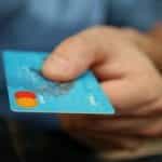 A hand holding out a blue debit card.