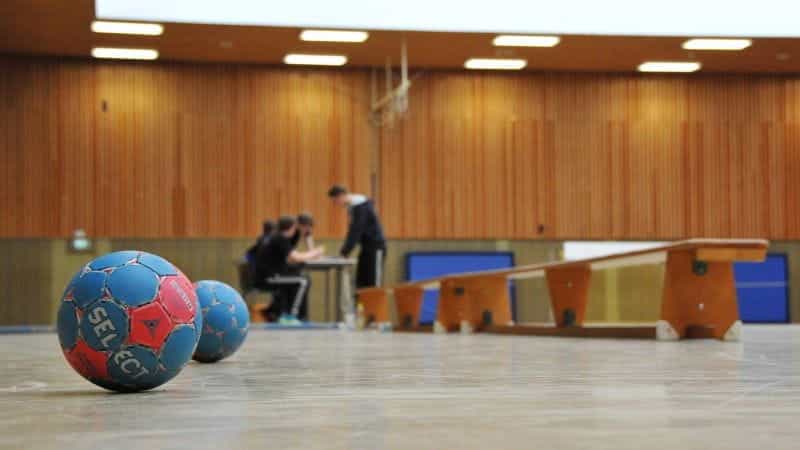 A pair of handball balls sitting next to one another inside of an indoor gym or handball court facility.