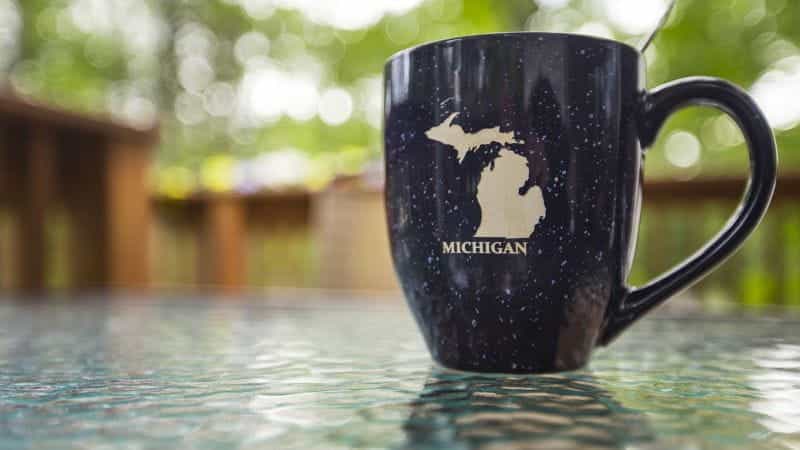 A mug reading Michigan under an image of the state sits on a table.
