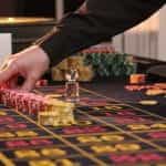 A dealer lines up stacks of chips on a roulette table in a casino.