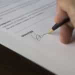 A business person signs a deal with a pen.