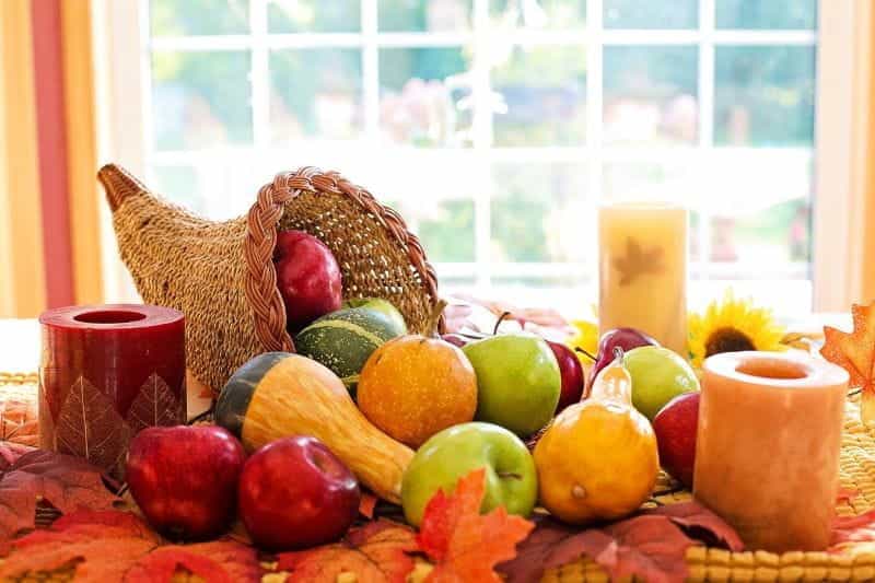 An overflowing cornucopia for Thanksgiving on a brightly-lit dinner table.