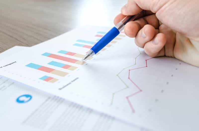A hand holding a pen pointing at a printed-out graph.