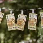 A series of €200 notes drying on a clothesline, held up by clothes pins.