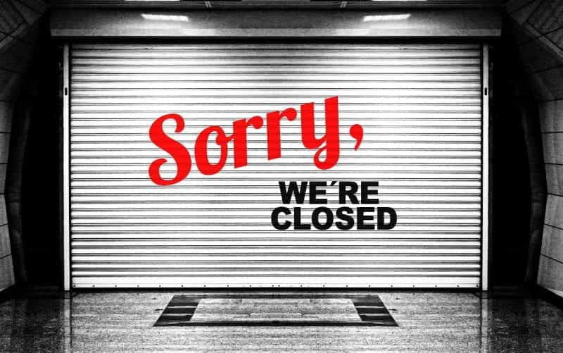 A shutter over a business reading SORRY, WE’RE CLOSED.