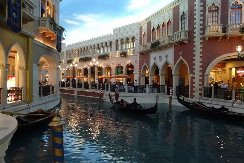 Seorang pendayung gondola mengarahkan gondola menyusuri kanal di Venesia.