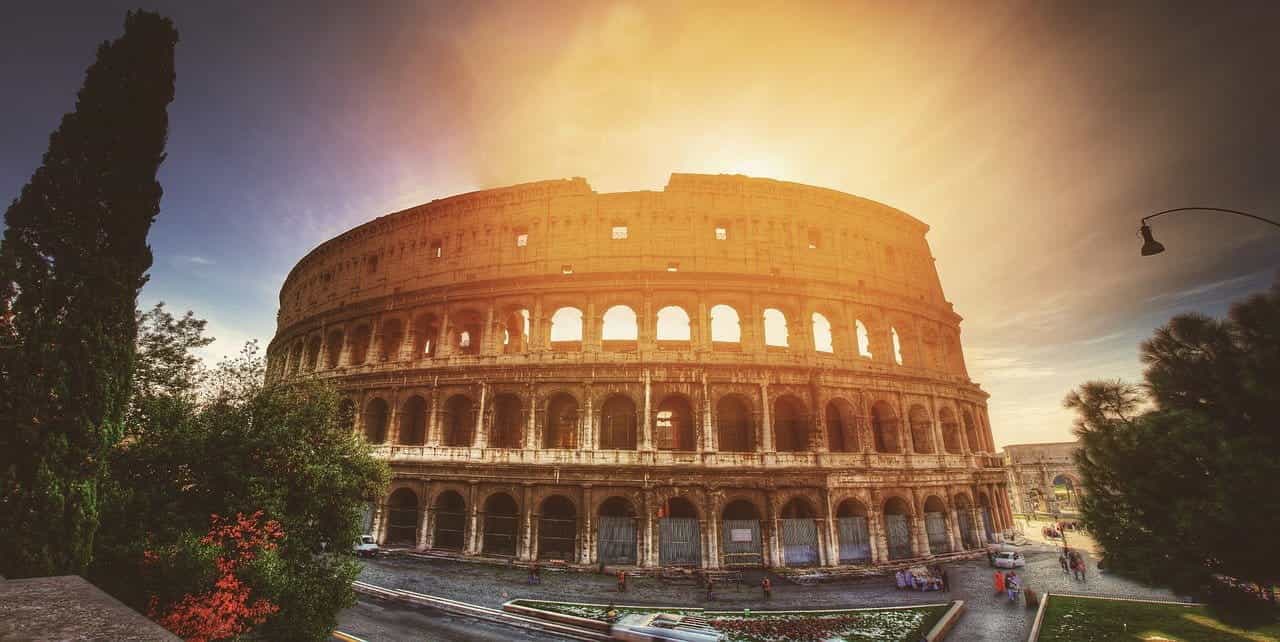 The world-famous Colosseum in Italy’s capital city of Rome, with the sun shining right directly behind it.