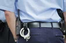 The backside of a police officer, equipped with a pair of handcuffs, a radio and a handgun.