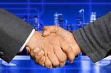 A handshake between two people in dark suits.