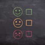 Three faces drawn on a chalkboard, ranging from smiling to satisfied to unhappy.