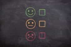 Three faces drawn on a chalkboard, ranging from smiling to satisfied to unhappy.