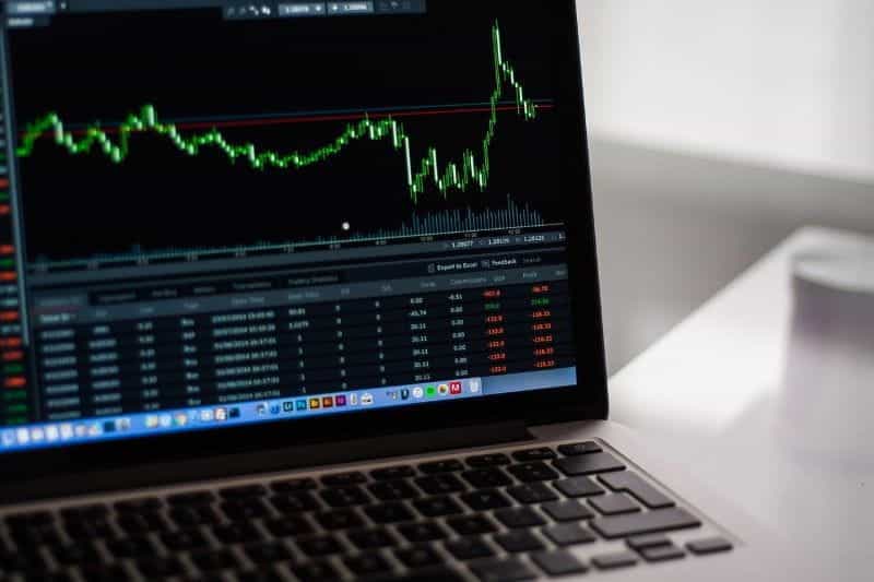 A laptop open to a window of a graph depicting a stock value rising and falling.