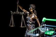 A statue of blind justice weighing its scales with a shopping cart in the foreground.