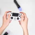 Hands holding a white PlayStation video game controller.