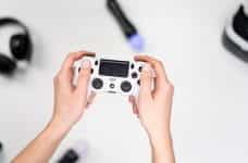 Hands holding a white PlayStation video game controller.
