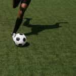 A footballer kicking a soccer ball.
