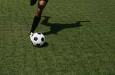 A footballer kicking a soccer ball.