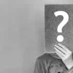 A person holding a rectangular form in front of their face with a large question mark on it.