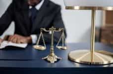 A judge or lawyer working at a desk, with scales of justice.