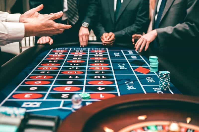 Pria berjas bermain roulette dengan chip di kasino.