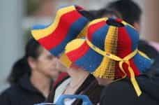 Two women wear celebratory hats colored like the Colombian flag for a national holiday.