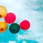 Balon merah, hijau, dan kuning dengan langit biru cerah.