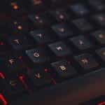 A close-up of a keyboard with red lighting underneath the keys.