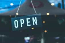 White text on a black sign in a glass window display says OPEN.