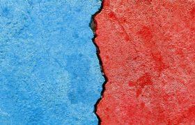 A wall part red, part blue, with a crack along the center dividing the colors.