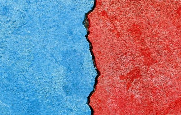 A wall part red, part blue, with a crack along the center dividing the colors.