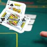 A closeup of a hand throwing cards in a poker game.