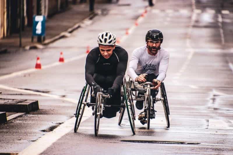Two wheelchair cyclists racing.