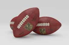 A trio of American footballs nestled together in a small group.