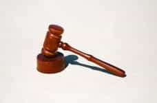 A judge’s gavel sits on a white surface.