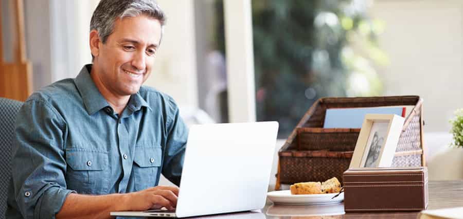 A man laughing with his laptop in front of him.