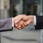 Two business people in suits shaking hands.