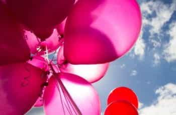 A bunch of pink balloons in the sky.