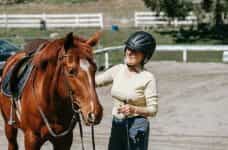 A jockey standing next to a racehorse.