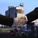 Two people in business suits shaking hands to finalize a partnership.