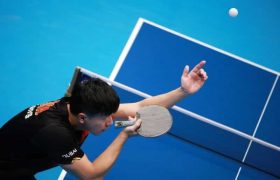 Tafeltennisser leunend over de tafel