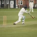 A front foot cover drive is played in a cricket match.
