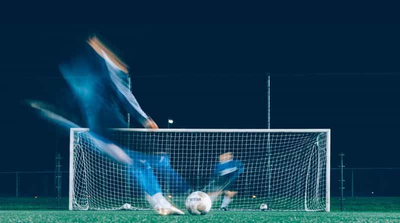 Footballer shooting towards a goal.