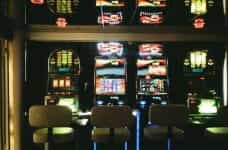 Four slot machines in a Casino with three chairs.