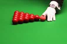 The referee, wearing a white glove, racking up the red balls ahead of a frame of snooker.
