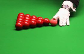 The referee, wearing a white glove, racking up the red balls ahead of a frame of snooker.