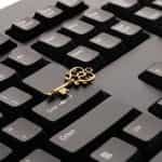 A golden key laying down flat on a computer keyboard.