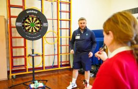 A schoolchild calculating maths whilst playing darts.