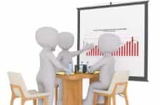 Three figures having a meeting in which one is showing the other two a bar graph of results.