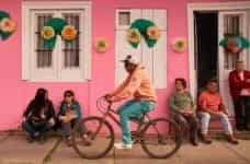 A man rides a bicycle in front of a pink building in Chile.