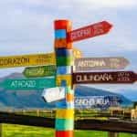 Colorful painted wood signs point the way to different cities on a mountain path in Province Pichincha, Ecuador.